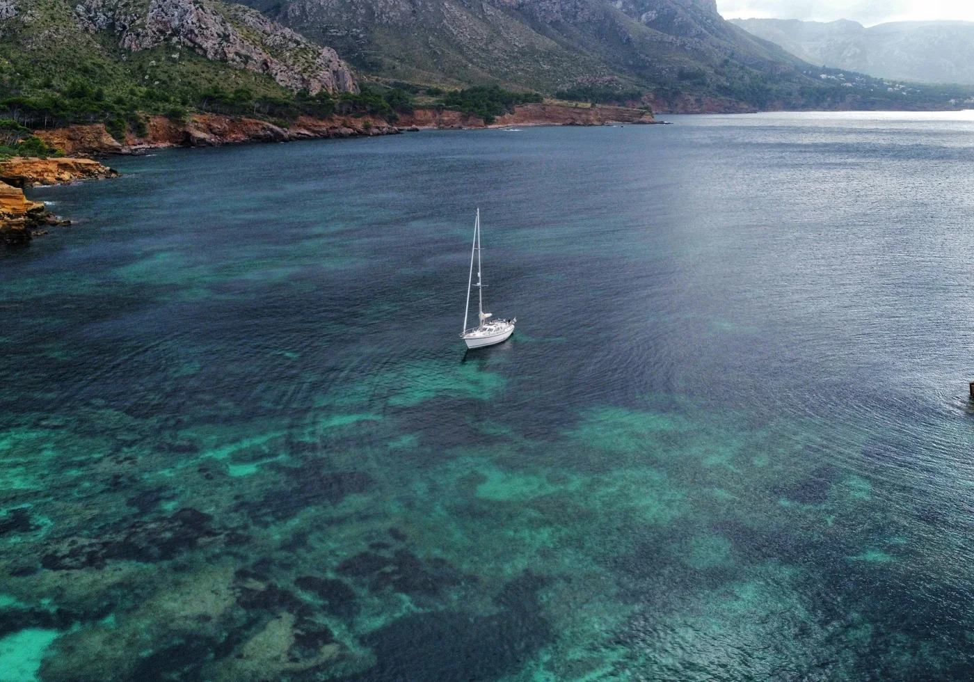 Sailboat anchored by the Mallorca coastline representing destination demand